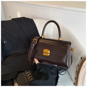 Dettaglio borsa vintage in pelle lucida testa di moro con fibbia dorata su divano