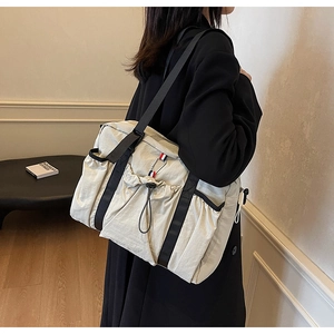 Dettaglio borsa tote in nylon beige con tasca a coulisse e moschettone in metallo