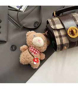 Dettaglio del ciondolo orsetto di peluche con sciarpa su una borsa Boston marrone
