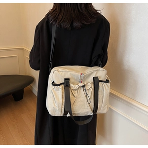 Dettaglio della borsa in nylon beige con tasca laterale a coulisse e ampia tracolla nera