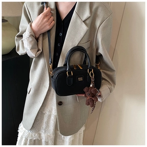 Detail of black nylon Boston bag with gold hardware and a cute brown bear charm