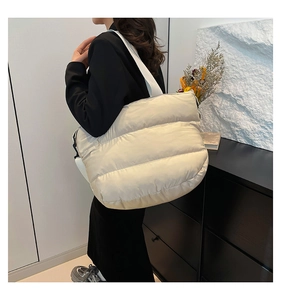 Sac cabas matelassé beige crème avec texture rembourrée et large bandoulière sur modèle