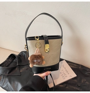 Detailed view of a stylish beige canvas bucket bag with black leather and monster charm