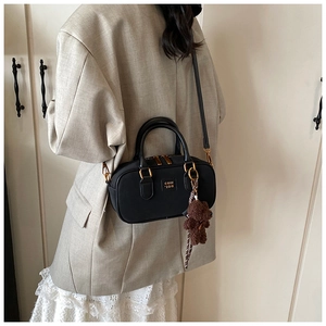 Model wearing a vintage black Boston bag with gold hardware and a cute bear charm
