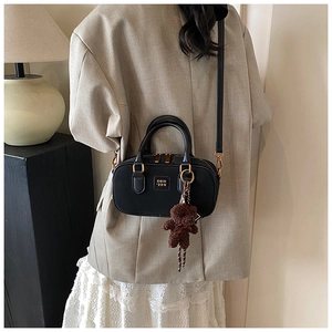 Close-up of a black Boston bag featuring a cute brown plush bear charm and gold hardware