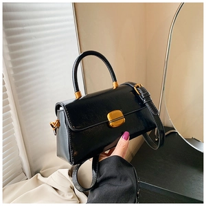 Dettaglio di una borsa vintage nera lucida con chiusura quadrata in metallo dorato