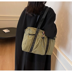 Dettaglio della borsa tote in nylon kaki con cinturino nero e fibbia laterale decorativa