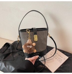 Detail of grey bucket bag with contrast leather trim, gold buckle and fuzzy monster charm