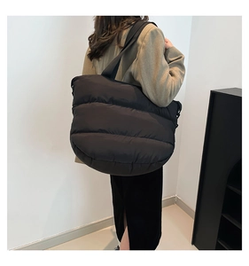 Détail du grand sac cabas matelassé noir porté à l'épaule pour un style quotidien