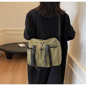 Grande borsa a tracolla verde oliva indossata su un cappotto nero lungo