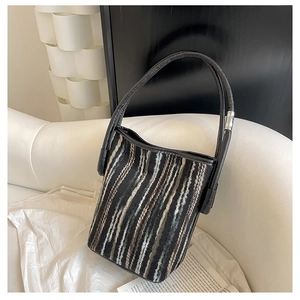 Nahaufnahme der gestreiften Eimer-Tasche mit Strickstruktur und schwarzem Ledergriff