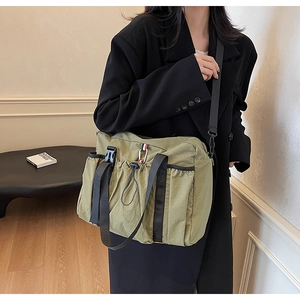 Dettaglio della borsa tote in nylon verde militare con fibbia tattica e tasca frontale