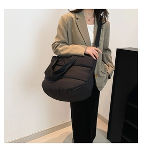 Détail du sac cabas matelassé noir avec une bandoulière large et réglable en tissu