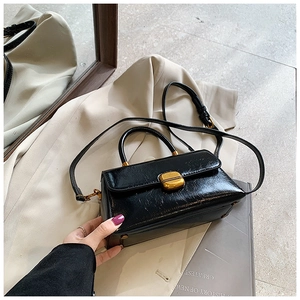 Dettaglio di borsa vintage in pelle nera lucida con elegante chiusura dorata