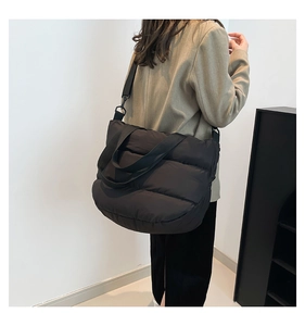 Détail d'un sac cabas noir matelassé montrant le nylon texturé et la bandoulière amovible