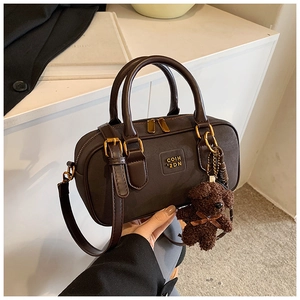 Close-up of vintage brown leather Boston bag with teddy charm and gold hardware