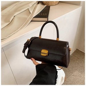Dettaglio di una borsa lucida marrone scuro con chiusura vintage dorata e manico