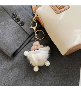 Plüschiger beige Anhänger mit brauner Strickmütze an weißer Leder-Beuteltasche