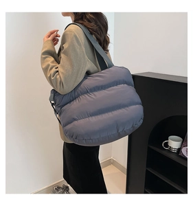 Détail d'un sac à bandoulière matelassé bleu gris avec une grande capacité de rangement