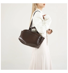 Detail of dark brown leather tote bag featuring elegant white contrast stitching for women