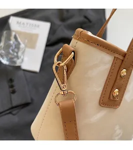 Makro-Detail der goldglänzenden Beschläge und cremefarbenen Lackleder-Oberfläche der Tasche