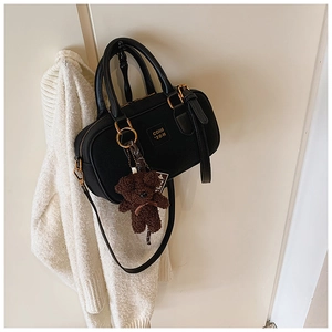 Detail of black vintage pillow bag with golden hardware and a cute plush bear charm