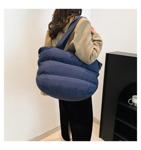 Sac fourre-tout matelassé bleu foncé porté par un mannequin dans un cadre moderne