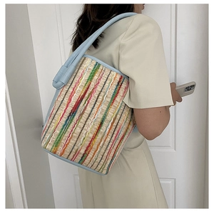 Detail der bunten gestreiften Stroh-Eimertasche mit hellblauem Leder-Schultergurt