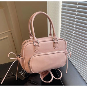 Close-up of soft pink matte leather bowling bag featuring side bow and metal zipper detail