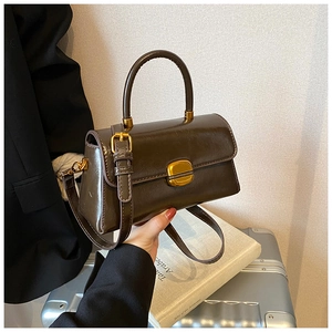 Dettaglio borsa a tracolla vintage marrone scuro con finitura lucida e fibbia dorata