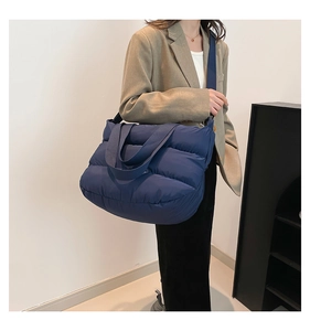 Détail du sac cabas matelassé bleu foncé avec bandoulière large porté par un mannequin