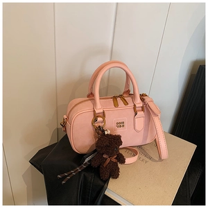 Pink Boston handbag with gold zipper detail and a cute plush bear charm accessory