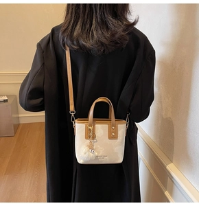 Detail einer minimalistischen zweifarbigen Beuteltasche mit Plüsch-Anhänger