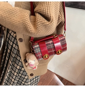 Dettaglio della borsa Boston scozzese rossa con ciondolo a orso indossata da modella
