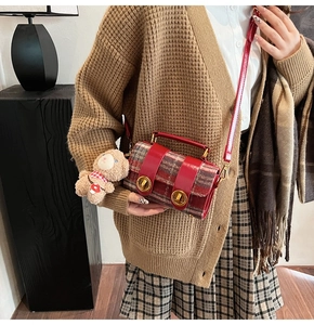 Dettaglio della borsa Boston in pelle rossa e tessuto scozzese con chiusure dorate e orsetto