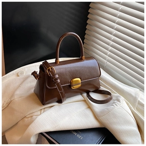 Dettaglio della borsa vintage in pelle marrone con chiusura dorata su un blazer