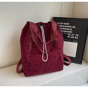 Detail of burgundy leopard print drawstring backpack with woven ropes and wide webbing straps