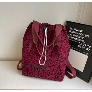 Detail of burgundy leopard print drawstring tote bag with wide straps on white background
