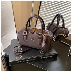 Detailed view of brown leather Boston bag with golden zipper and adjustable strap