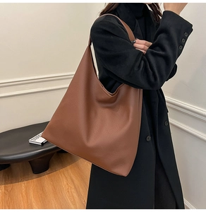 Close-up of caramel brown pebble leather tote bag on black wool coat for autumn style