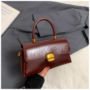 Dettaglio macro della borsa vintage rosso vino in pelle cerata con serratura dorata
