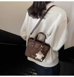 Rückansicht einer dunkelbraunen Beuteltasche am Model mit süßem Plüschpuppen-Anhänger