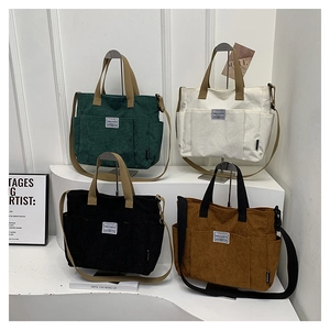 Detail view of corduroy tote bags in four colors with dual handles and spacious front pockets