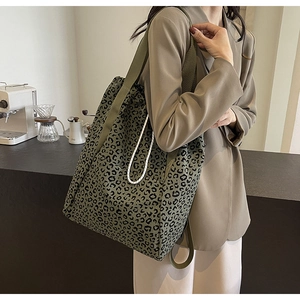 Olive green leopard print canvas tote bag with side rope detail shown on a model