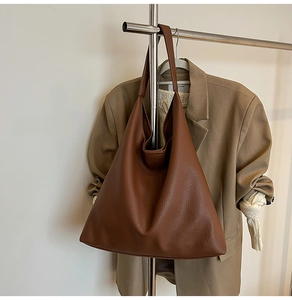 Detail of dark brown lychee texture leather tote bag with a natural draped silhouette