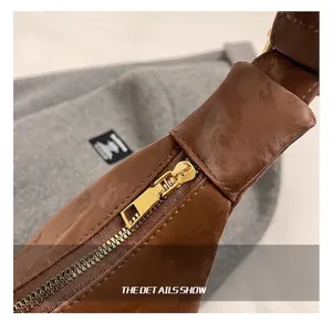 Detail shot of golden metal zipper and embossed leather texture on brown handbag