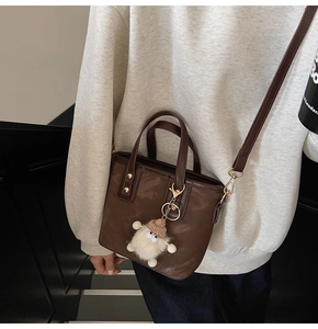 Braune Leder-Eimertasche mit Tragegriffen, Goldnieten und süßem Plüsch-Anhänger