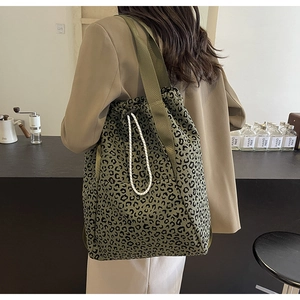 Detail of leopard print tote bag with white drawstring on a model in a cafe setting