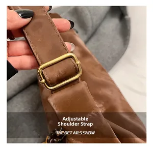 Detail shot of a brown leather bag showing the adjustable strap with golden metal buckle
