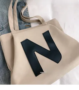 Top-down close-up of beige canvas tote bag with a bold black letter N patch detail